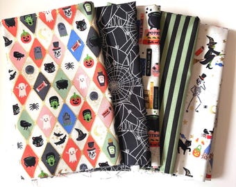 Könnte beinhalten: Eine Sammlung von Stoffpaketen zum Thema Halloween. Die Stoffe weisen verschiedene Muster auf, darunter Rauten mit Halloween-Symbolen, Spinnennetze, Zaubertränke und Streifen. Zu den Farben gehören Schwarz, Weiß, Orange, Grün und Rosa. Die Pakete sind gefaltet und gestapelt.
