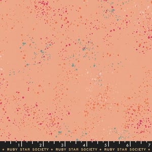 May include: Peach-colored fabric with a speckled pattern. The fabric is covered in small, irregular dots of various colors, including pink, orange, teal, and white. The dots are scattered across the surface, creating a playful and textured design.