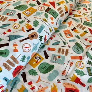 May include: Fabric featuring a camping-themed pattern on a white background. The design includes illustrations of campfires, compasses, guitars, arrows, and the words "Field Notes," "Camp," "Lake," and "Fields." Ideal for crafting and sewing projects.