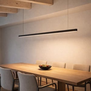 Puede incluir: Un comedor moderno con una mesa larga y rectangular de madera y seis sillas tapizadas. Sobre la mesa cuelga una elegante lámpara colgante lineal negra, que ilumina el espacio. Un cuenco de fruta está sobre la mesa.