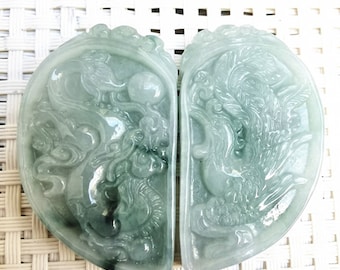 May include: Two jade green pendants carved in the shape of a heart, each with a detailed dragon design. The pendants are separated and facing each other.