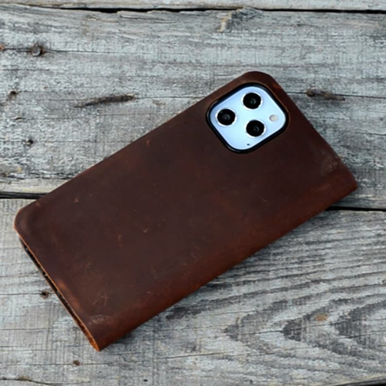 May include: A brown leather phone case with a camera cutout for a smartphone with a triple lens camera system.