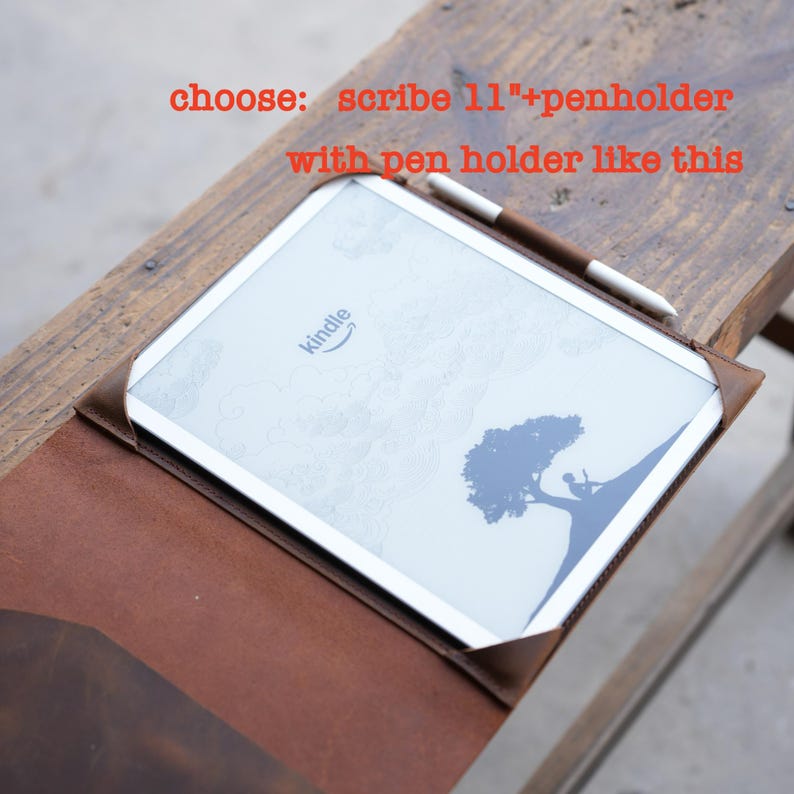 May include: A brown leather Kindle Scribe 11" case with a pen holder. The Kindle is white with a tree graphic and the Amazon Kindle logo. A brown and white stylus rests on the screen. Text in the image reads: "choose: scribe 11"+penholder with pen holder like this."