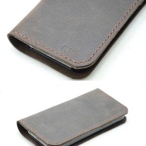 May include: A brown leather phone case with stitching around the edges. The case has the initials "C.J.F." embossed on the front.