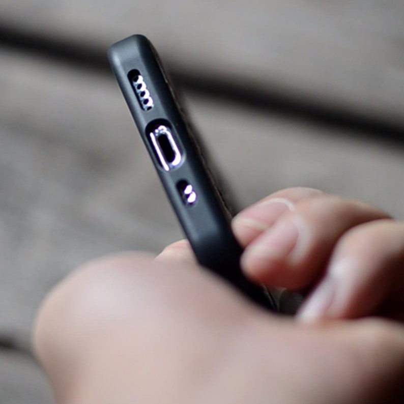 May include: A black phone case with a textured surface and a cutout for the charging port.