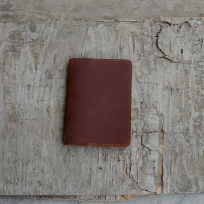 Puede incluir: Un cuaderno de cuero marr&oacute;n con un borde cosido.