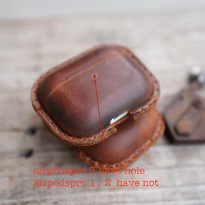 May include: Brown leather Airpods Pro case with a stitched border. The case has a hole on the top. Text on the image reads: "airpodspro 3 have hole airpodspro 1 / 2 have not."