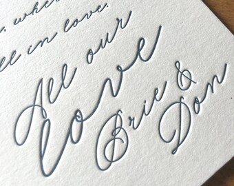 May include: A cream-colored card with dark gray debossed cursive text that reads: the magic wonderful where we in love. All our LOVE Brie & Don. The card features a textured paper surface and a circular stamp design in the top left corner.