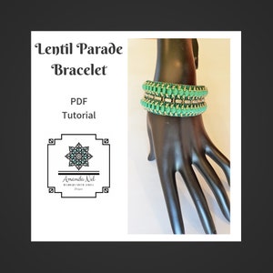 Könnte beinhalten: Ein PDF-Tutorial für ein Perlenarmband namens "Lentil Parade Bracelet" von Amanda Nel Designs. Das Armband ist aus grünen und silbernen Perlen gefertigt und wird auf einer schwarzen Mannequinhand gezeigt.
