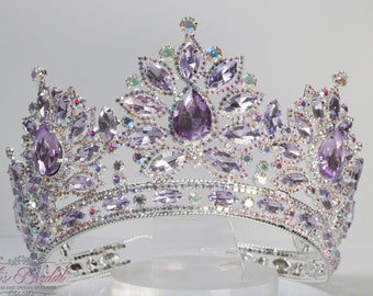 May include: A silver-toned crown with a dazzling array of purple and clear crystals. The crown features large, teardrop-shaped purple stones and smaller, iridescent crystals, creating a sparkling effect. The crown is designed for special occasions.