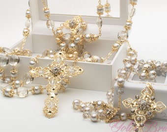 May include: A white box containing a gold and crystal rosary. The rosary features a large gold cross with crystals. The box is open, showcasing the rosary. The box has the words "Gold Bridal" and "Baptism & Special Occasion" printed on it.