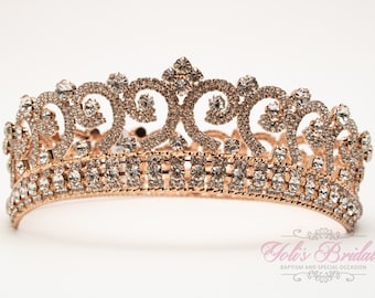 Puede incluir: Una tiara de oro rosa con diamantes de imitación transparentes. La tiara tiene un diseño delicado con detalles intrincados.