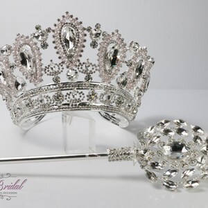 Op de afbeelding: Een zilveren kroon met roze en heldere strass steentjes, en een bijpassende zilveren scepter met heldere strass steentjes.