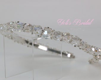 May include: A silver headband with clear crystal beads. The headband is on a clear acrylic stand.