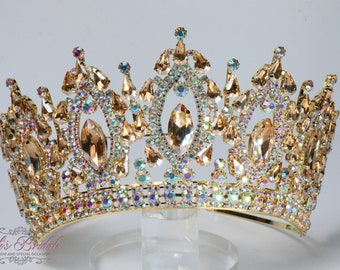 Puede incluir: Una corona dorada con un diseño grande y ornamentado. La corona está decorada con diamantes de imitación transparentes y color champán.
