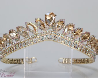 Puede incluir: Una tiara dorada con diamantes de imitación transparentes y color champán. La tiara tiene un diseño delicado con forma de hoja y es perfecta para una ocasión especial.