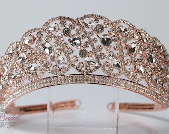 Puede incluir: Tiara de oro rosa con diamantes de imitación transparentes. La tiara tiene un diseño delicado e intrincado con una fila de diamantes de imitación más pequeños alrededor de la base.