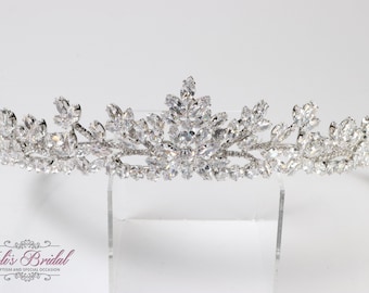 May include: A silver tiara with a floral design, featuring a large cluster of clear rhinestones in the center.