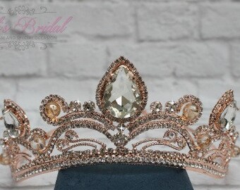 Puede incluir: Una tiara de oro rosa con diamantes de imitación transparentes y ámbar. La tiara tiene un diseño delicado y adornado y es perfecta para una ocasión especial.
