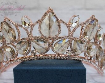 Puede incluir: Una tiara de oro rosa con adornos de cristal transparente. La tiara está hecha de metal y tiene un diseño delicado.