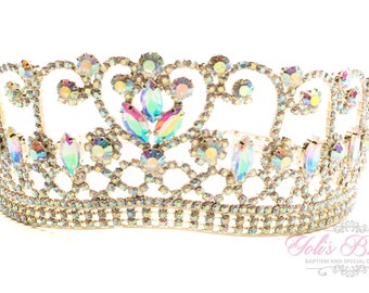 May include: A gold crown with iridescent rhinestones. The crown has a delicate design with a heart shape in the center.