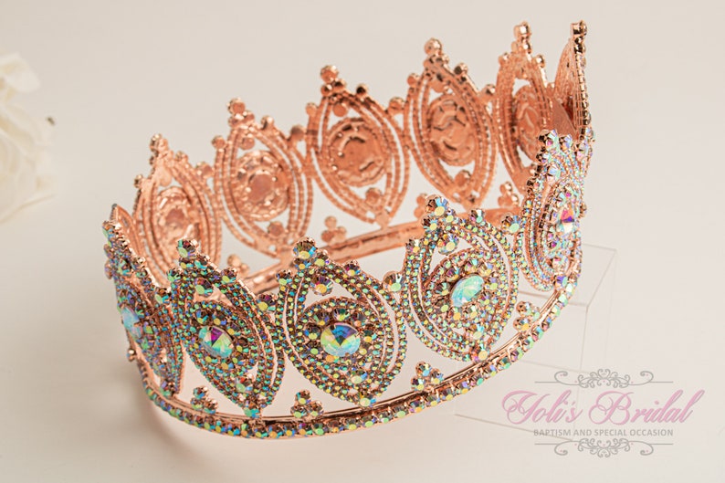 May include: A rose gold crown with iridescent rhinestones. The crown has a delicate, ornate design and is perfect for a special occasion.