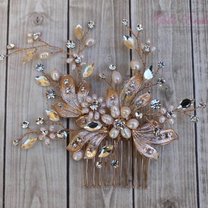 Può includere: Pettine per capelli dorato con decorazioni di perle e cristalli. Il pettine presenta un design floreale con foglie e fiori.