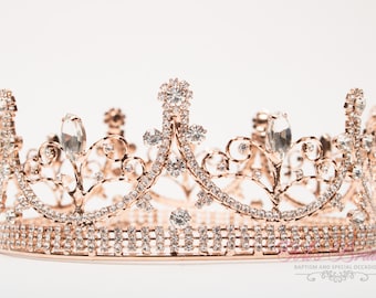 Puede incluir: Una corona de oro rosa con brillantes transparentes y un delicado diseño floral. La corona está adornada con una banda de brillantes más pequeños alrededor de la base.