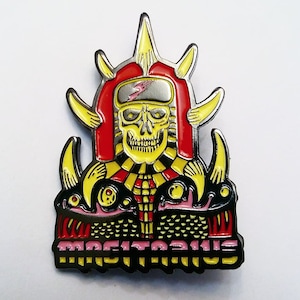 May include: A black and yellow enamel pin featuring a skull wearing a red and yellow helmet with a lightning bolt design. The skull is surrounded by yellow and black horns and the text "MORTICIAN" is printed below.