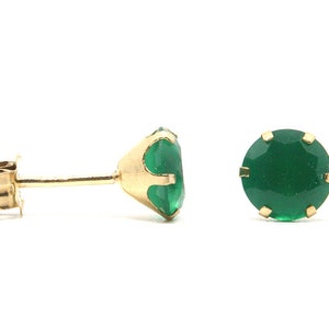 Puede incluir: Un par de pendientes de oro con piedras preciosas verdes.