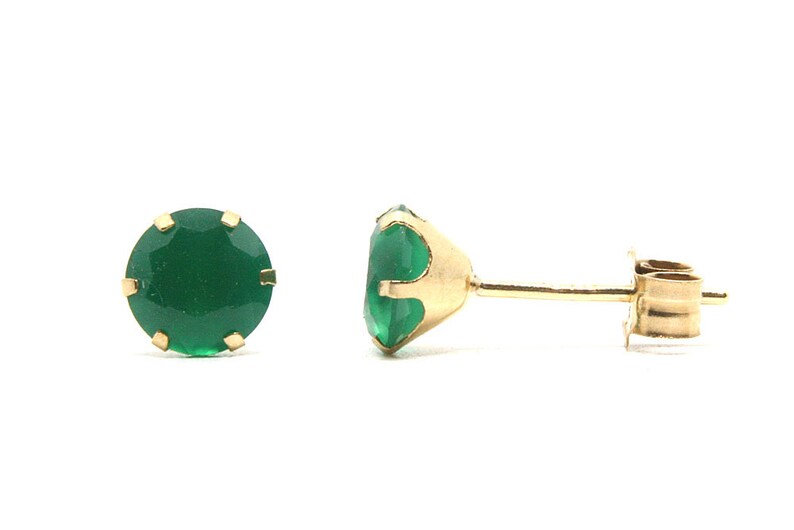 Puede incluir: Un par de pendientes de oro con piedras preciosas verdes.