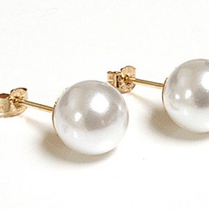 May include: A pair of gold stud earrings with white pearl accents.