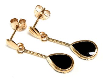 May include: A pair of gold earrings with black teardrop-shaped stones.