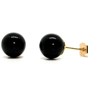 May include: A pair of black gemstone stud earrings with gold posts.