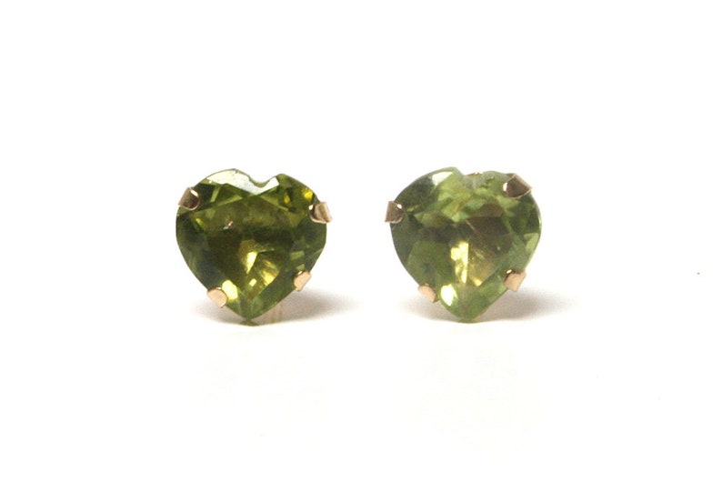 May include: A pair of heart-shaped green peridot earrings with gold settings.