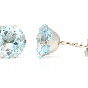 May include: A pair of silver stud earrings with light blue round gemstones.