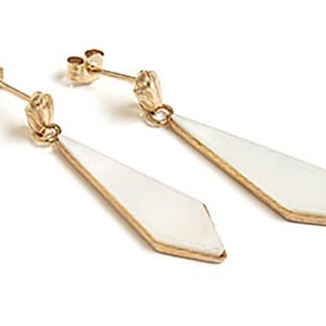 May include: A pair of gold earrings with white diamond-shaped pendants. The earrings have a simple design and are perfect for everyday wear.