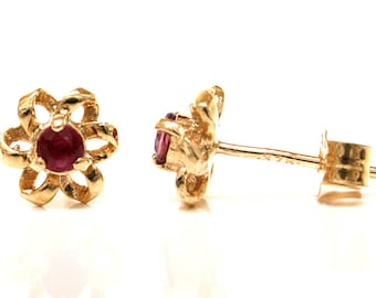 May include: A pair of gold flower-shaped earrings with a red gemstone in the centre of each flower.