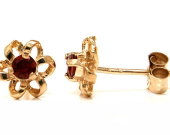 May include: A pair of gold flower-shaped earrings with red gemstone accents.