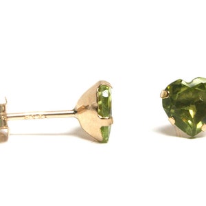 May include: A pair of gold heart-shaped earrings with green gemstones