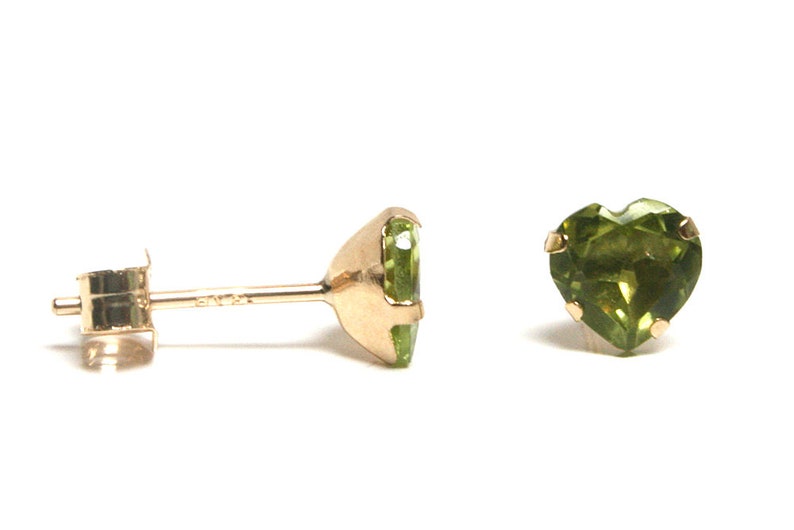 May include: A pair of gold heart-shaped earrings with green gemstones