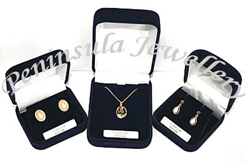May include: Three black velvet jewelry boxes with white interior lining. The boxes contain gold earrings, a gold necklace with a pendant, and gold dangle earrings.