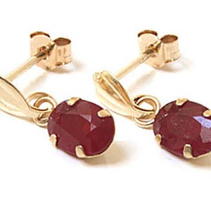 May include: A pair of gold earrings with dangling red oval-shaped gemstones.