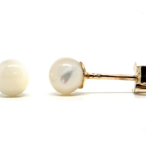 Puede incluir: Un par de pendientes de oro con perlas. Las perlas son blancas y redondas.