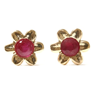 May include: A pair of gold flower-shaped earrings with red ruby gemstones in the centre.
