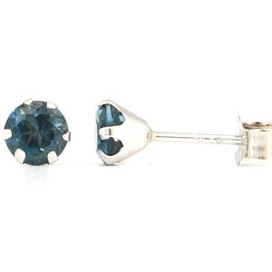 Puede incluir: Un par de pendientes de plata con una piedra preciosa redonda azul en cada pendiente.