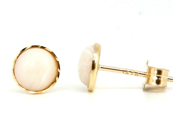 May include: A pair of gold earrings with white round stones set in a gold bezel. The earrings have a post back.