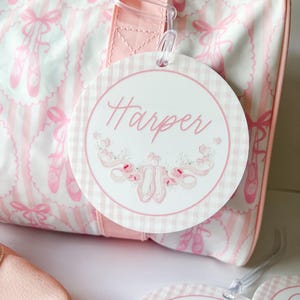 May include: Pink and white ballet-themed duffel bag with a pink and white gingham luggage tag that says "Harper" in pink cursive lettering.