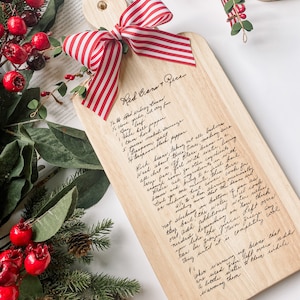 May include: A wooden cutting board with a red and white striped ribbon tied around the top. The board has a handwritten recipe for "Red Beans & Rice" inscribed on the surface.