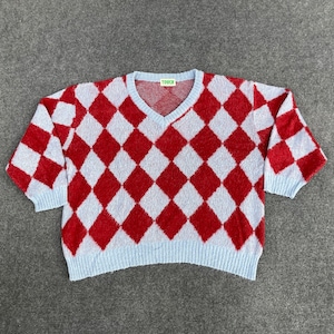 May include: A blue and red checkered sweater with a v-neck and the word "TOUCH" on the tag.